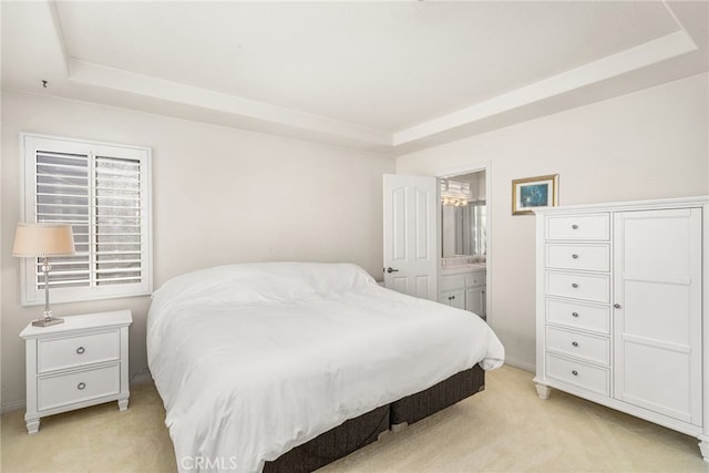 carpeted bedroom with connected bathroom and a tray ceiling