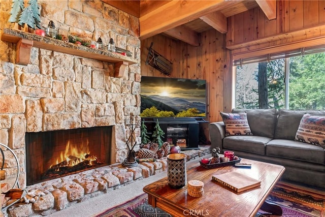 living room with beam ceiling, wood walls, and a stone fireplace