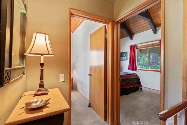 hallway featuring light carpet, wood ceiling, and vaulted ceiling with beams