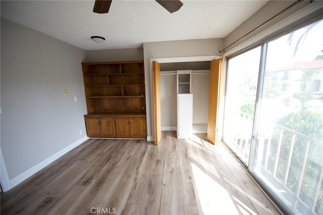 unfurnished bedroom featuring a textured ceiling, a closet, ceiling fan, and light wood-type flooring