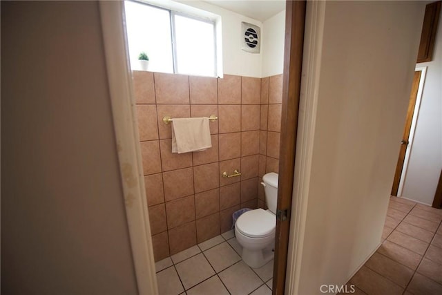 bathroom featuring tile patterned flooring, tile walls, and toilet