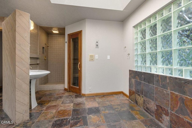 bathroom featuring tile walls, a textured ceiling, tile floors, and a tile shower