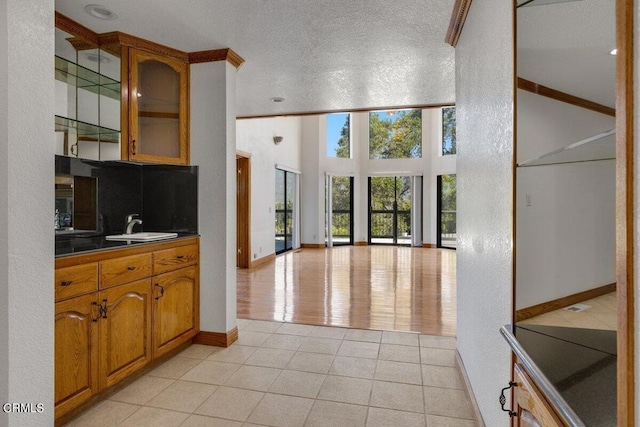 kitchen with sink, a towering ceiling, a textured ceiling, and light tile flooring