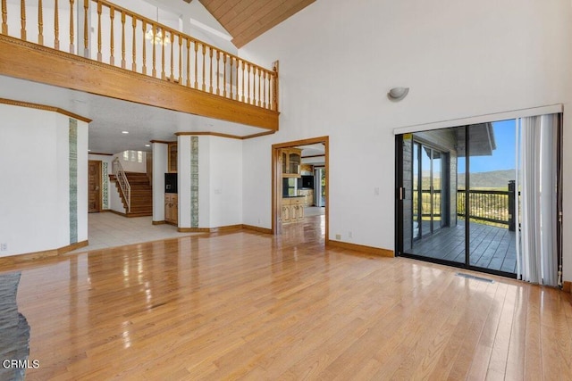 unfurnished living room with high vaulted ceiling and light hardwood / wood-style flooring