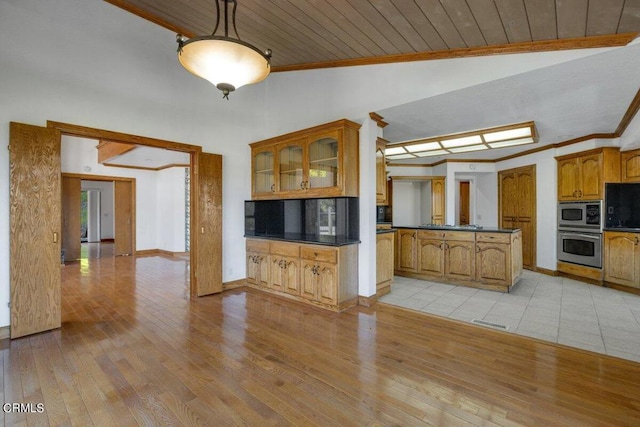 kitchen with decorative light fixtures, vaulted ceiling with skylight, stainless steel appliances, light tile floors, and wood ceiling