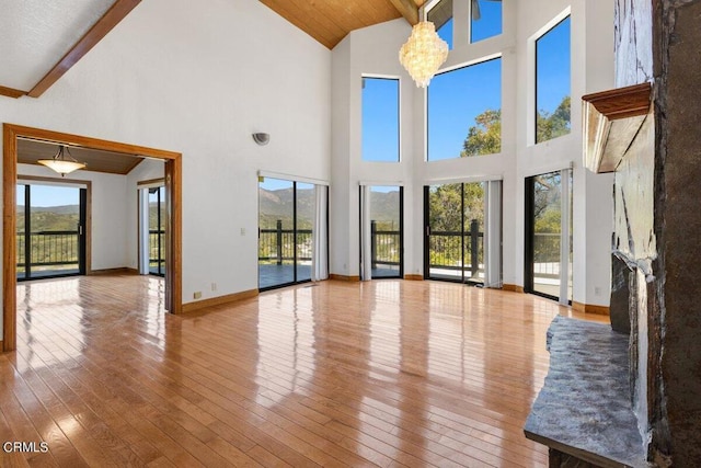 unfurnished living room with beamed ceiling, wood-type flooring, a healthy amount of sunlight, and high vaulted ceiling