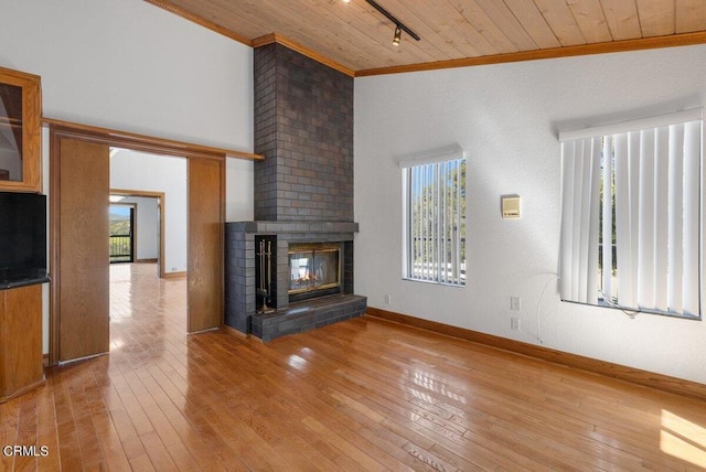 unfurnished living room featuring light hardwood / wood-style flooring, brick wall, track lighting, wood ceiling, and a fireplace