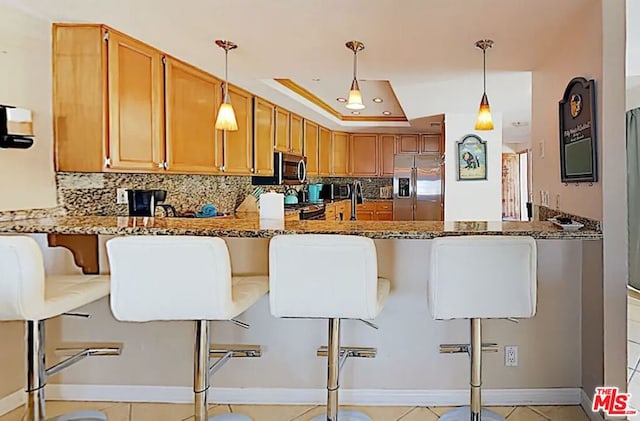 kitchen with stainless steel appliances, stone counters, and a breakfast bar area