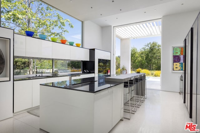 kitchen with white cabinetry, sink, plenty of natural light, and a center island