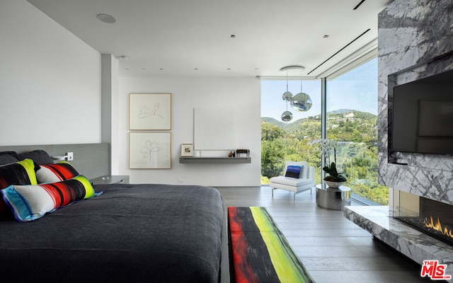 bedroom featuring expansive windows, a fireplace, and hardwood / wood-style floors