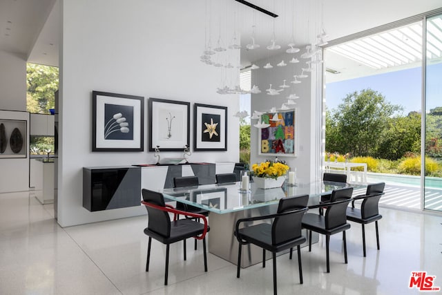 dining area featuring a towering ceiling, a healthy amount of sunlight, and a wall of windows