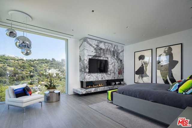 bedroom with expansive windows, wood-type flooring, and a premium fireplace