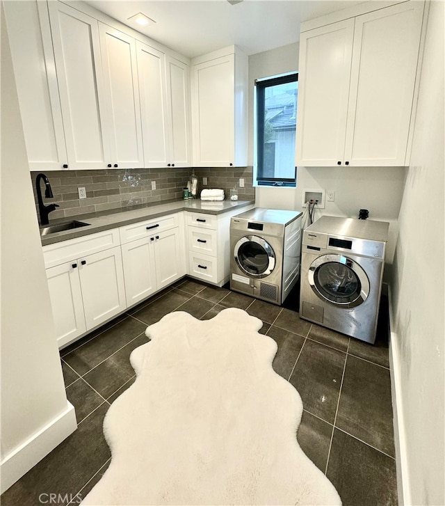 washroom with cabinets, sink, washing machine and clothes dryer, and dark tile patterned floors