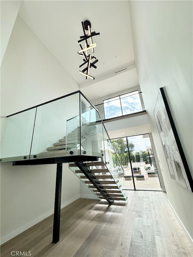 staircase with a notable chandelier, hardwood / wood-style flooring, and a high ceiling