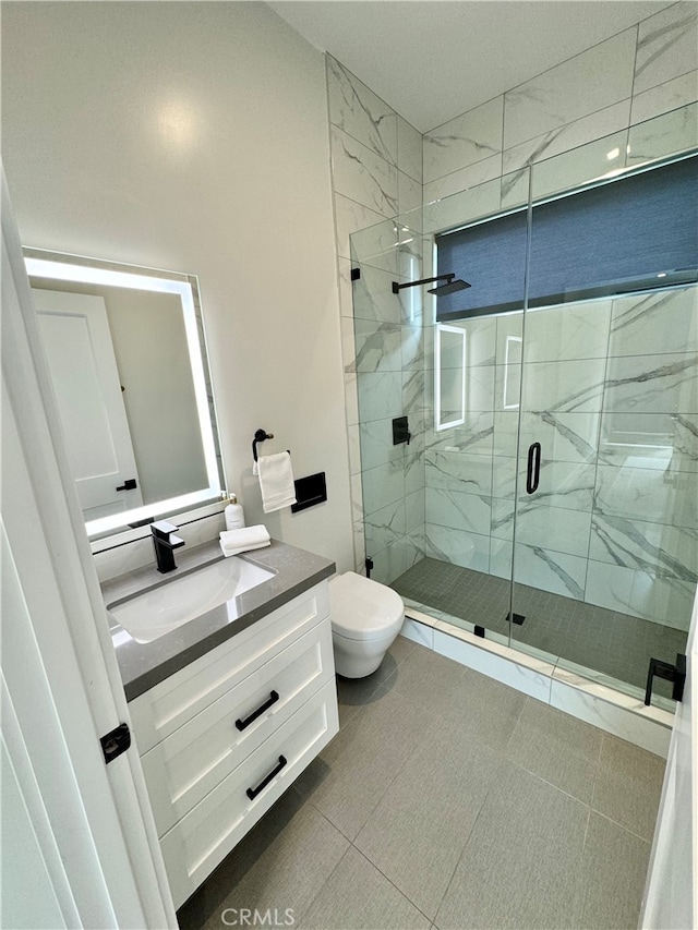 bathroom with vanity, toilet, tile patterned floors, and a shower with door