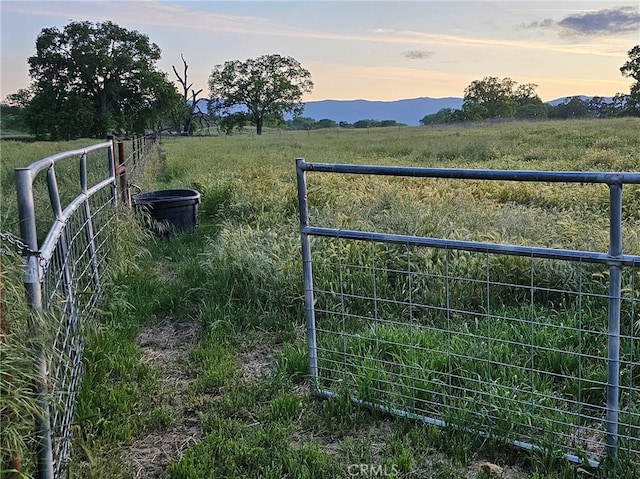 gate at dusk featuring a mountain view and a rural view