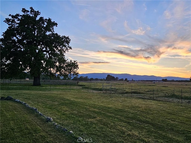 yard at dusk featuring a mountain view and a rural view