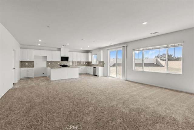 unfurnished living room featuring plenty of natural light and carpet