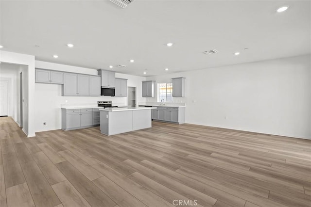 kitchen with gray cabinetry, electric stove, and a kitchen island