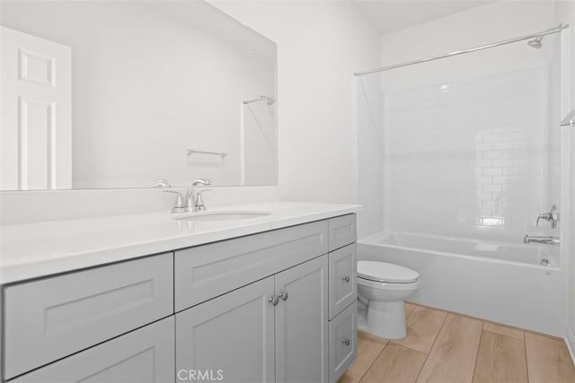 full bathroom with hardwood / wood-style flooring, vanity, washtub / shower combination, and toilet