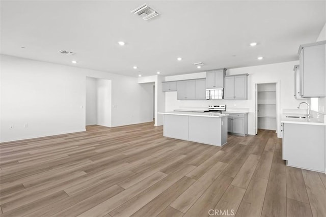 kitchen featuring sink, gray cabinetry, a center island, light hardwood / wood-style floors, and stainless steel electric range