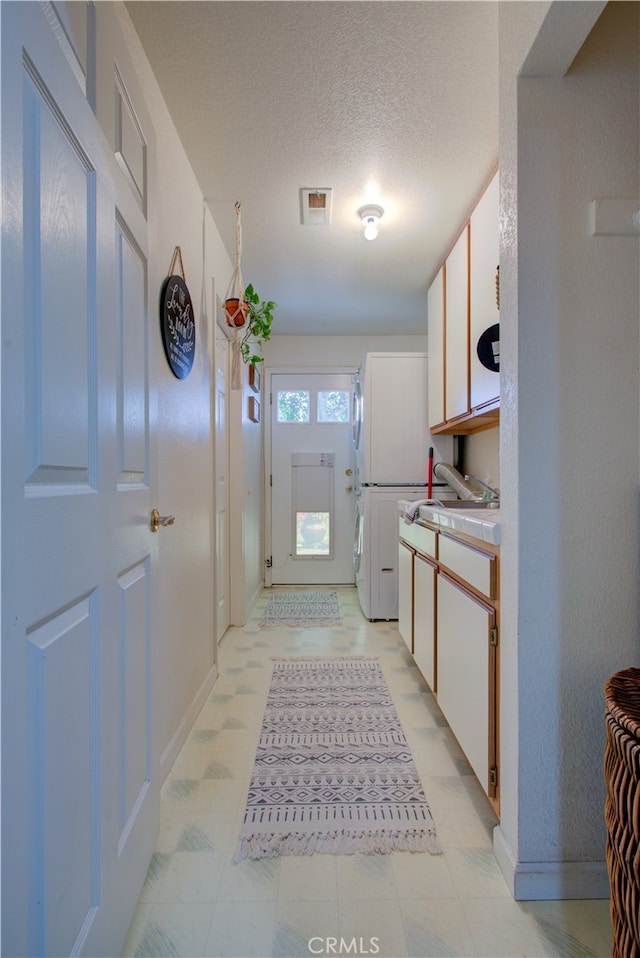 kitchen with white cabinets, a textured ceiling, sink, and light tile floors