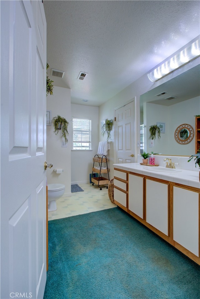 bathroom with toilet, vanity, and a textured ceiling