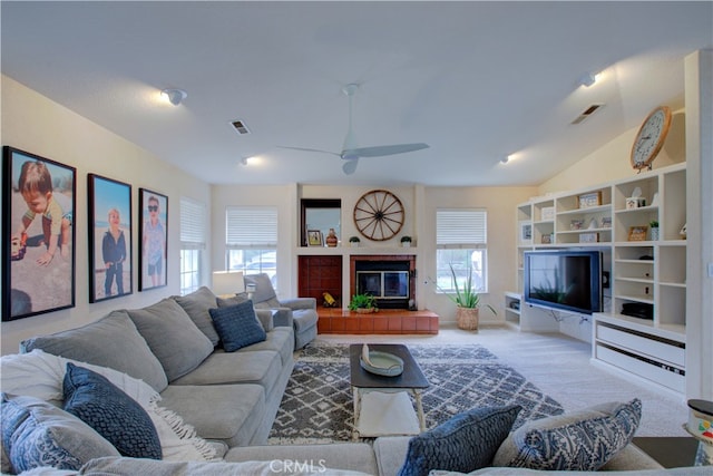 carpeted living room with vaulted ceiling, ceiling fan, and a tiled fireplace