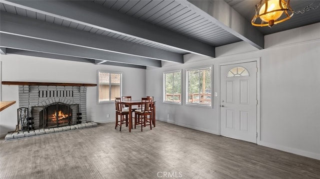 interior space featuring a brick fireplace, beam ceiling, and wood-type flooring