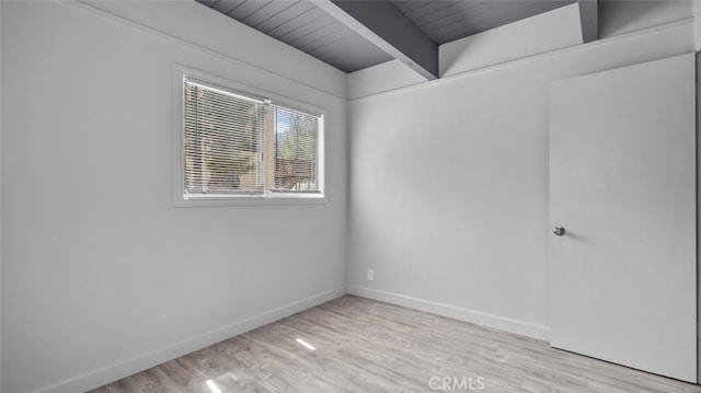 empty room with light wood-type flooring and beam ceiling