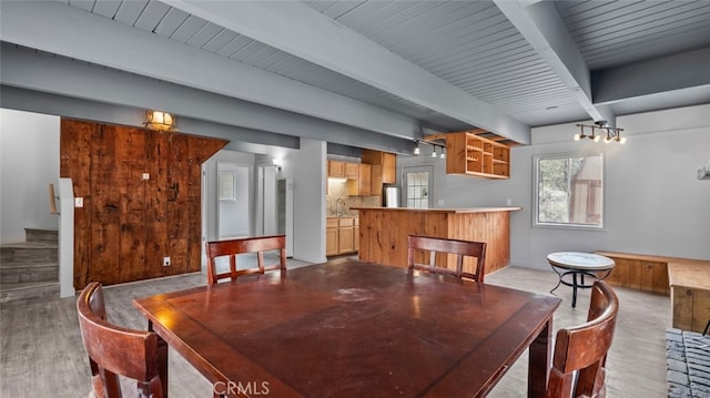 dining area featuring beamed ceiling, sink, and light hardwood / wood-style floors