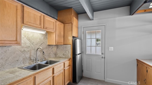 kitchen with sink, wood ceiling, stainless steel fridge, beam ceiling, and decorative backsplash