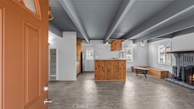 kitchen featuring a brick fireplace, beam ceiling, and dark wood-type flooring