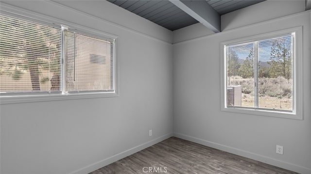 unfurnished room featuring beamed ceiling, a healthy amount of sunlight, and hardwood / wood-style floors