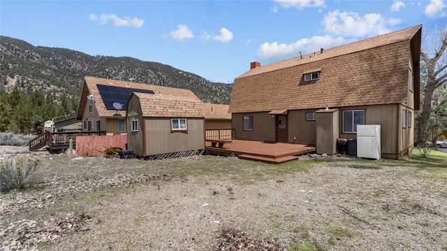 back of house with a deck with mountain view and solar panels