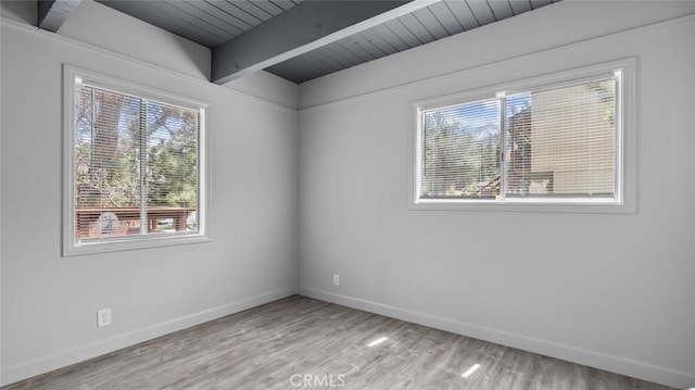 empty room featuring beam ceiling and light hardwood / wood-style flooring