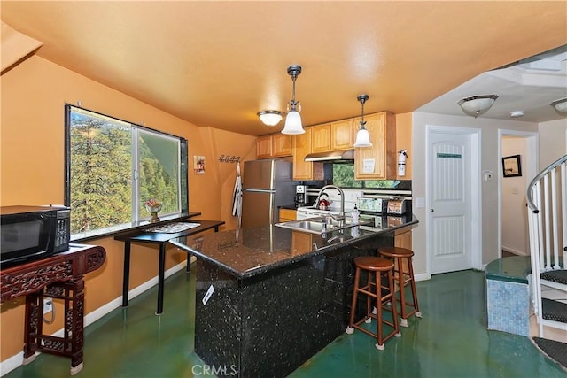 kitchen with stainless steel fridge, a breakfast bar, sink, pendant lighting, and dark stone countertops