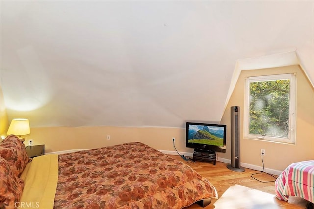 bedroom with vaulted ceiling and light hardwood / wood-style flooring