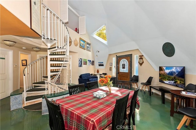 dining space with high vaulted ceiling and concrete floors