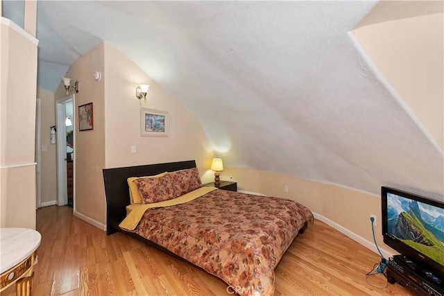 bedroom featuring lofted ceiling and light wood-type flooring