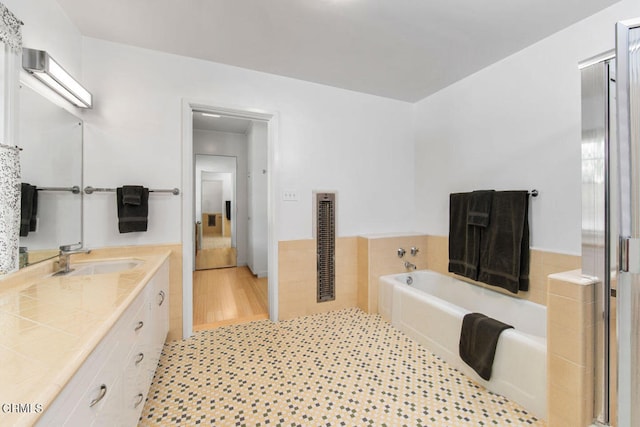 bathroom featuring wood-type flooring, oversized vanity, and shower with separate bathtub