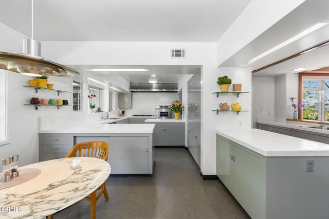 kitchen with oven, gray cabinetry, kitchen peninsula, sink, and tasteful backsplash