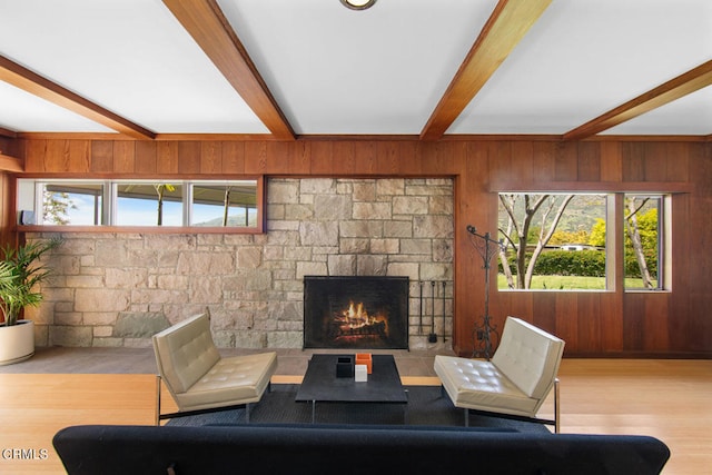 living room with a fireplace, beam ceiling, wood walls, and hardwood / wood-style flooring