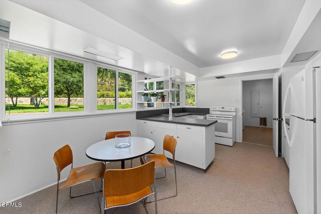 kitchen with white cabinetry, kitchen peninsula, white appliances, and sink