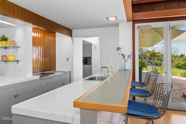 kitchen with sink, gray cabinetry, tile countertops, and hardwood / wood-style floors