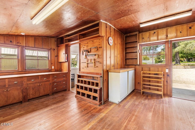 interior space with vaulted ceiling, light hardwood / wood-style floors, and wooden walls