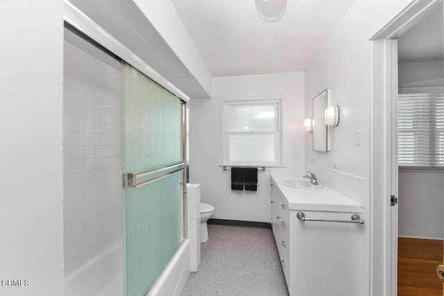 full bathroom featuring vanity with extensive cabinet space, wood-type flooring, toilet, and combined bath / shower with glass door