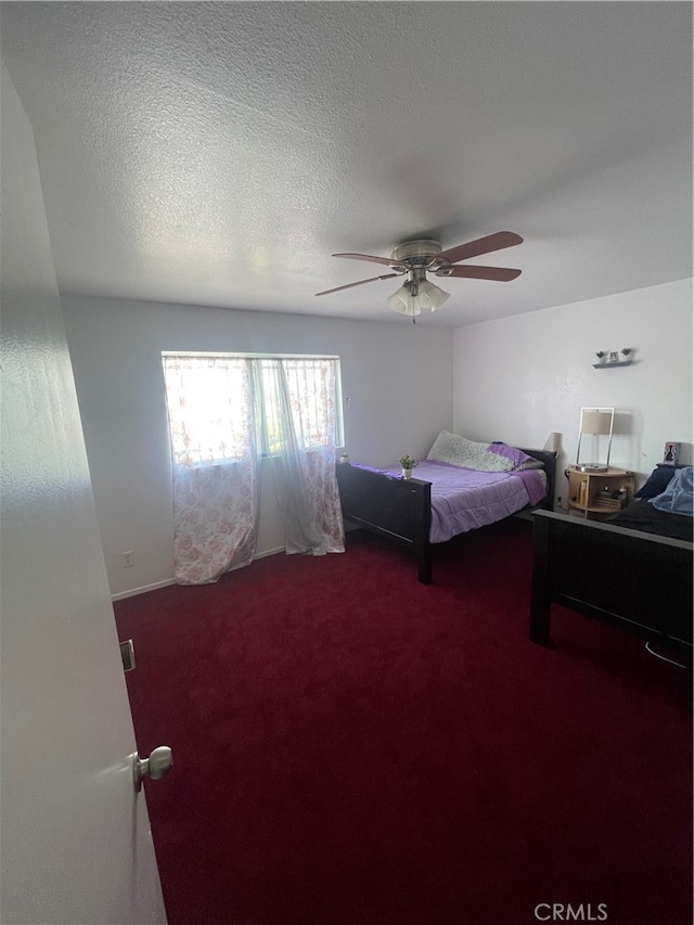 bedroom with ceiling fan, carpet, and a textured ceiling