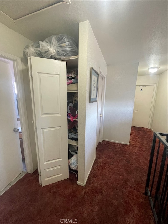 hallway featuring dark colored carpet