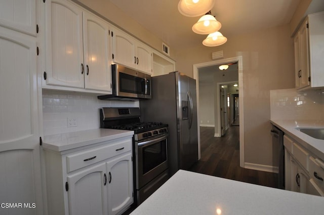 kitchen with appliances with stainless steel finishes, tasteful backsplash, white cabinetry, and dark hardwood / wood-style floors